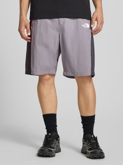 Mężczyzna nosi Shorts mit Logo und Gürtel von The North Face, krój regular fit, pasek, elastyczny pas, szerokość w rozmiarze M 42 cm, długość nogawki wewnętrznej 24 cm, widok całej sylwetki z przodu.