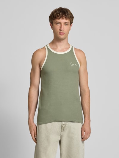 Męski model nosi Slim Fit Top mit Logo-Stitching od KARL KANI z czystej bawełny, strukturalny wzór, okrągły dekolt, krój slim fit, zielony z kremowymi lamówkami, długość tyłu w rozmiarze M: 68 cm, widok całej sylwetki z przodu.