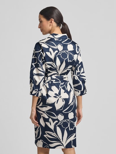 Modelka nosi Regular Fit Midikleid mit floralem Allover-Print von Betty Barclay, granatowo-biały wzór kwiatowy, czysta bawełna, długość do kolan, pasek w talii, półdługie rękawy, guzikowanie, widok całej sylwetki od tyłu. Szerokość w rozmiarze 36: 51 cm, długość tyłu: 100 cm, długość rękawa: 46 cm.