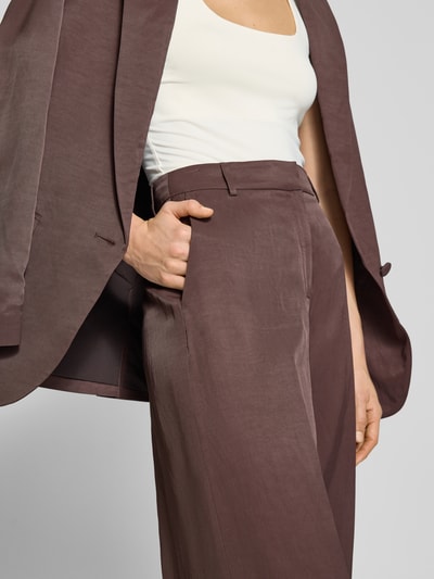 Vrouwenmodel draagt Straight Fit Stoffhose mit Bügelfalten van Jake*s Cocktail in bruin met steekzakken en persvouwen, detailopname taille.