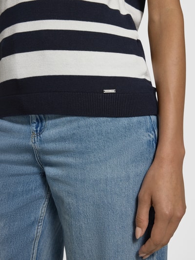 Frauenmodel trägt Strickshirt mit Rundhalsausschnitt und Label-Detail von More & More, gestreift, Viskose-Elasthan, Nahaufnahme Oberkörper.