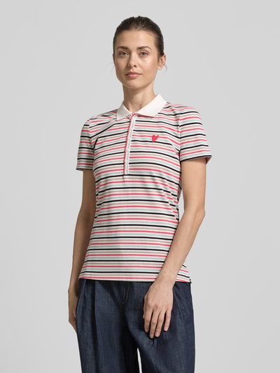 Kobiece modelka nosi Regular Fit Poloshirt aus Baumwoll-Mix od Tom Tailor, efekt: wzór w paski, wyhaftowany motyw, kołnierzyk polo, dekolt w serek, listwa guzikowa, krótki rękaw, pika, mieszanka bawełny, widok całej sylwetki z przodu.