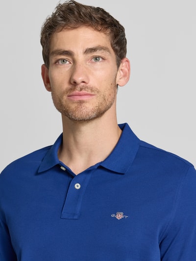 Männermodel trägt Regular Fit Poloshirt aus reiner Baumwolle von GANT in Blau, strukturierte Oberfläche, Nahaufnahme Oberkörper.