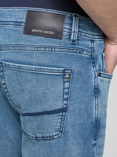 Mężczyzna nosi Tapered Fit Jeans im Used-Look Modell 'Lyon' od Pierre Cardin, bawełniany miks z domieszką wiskozy, używany wygląd, jasnoniebieski kolor, tylna kieszeń z kontrastowym przeszyciem, szerokość w rozmiarze 32/32: 42 cm, długość nogawki wewnętrznej: 79 cm, zbliżenie na tył jeansów.