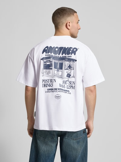 Männermodel trägt Regular Fit T-Shirt mit Logo-Stitching von ANOTHER COTTON LAB, weiß mit dunkelblauem Rückenprint, Ganzkörperansicht Rückansicht.