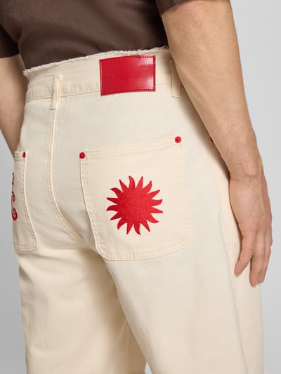 Männermodel trägt Jorts mit Stitching und Fransen von ANOTHER COTTON LAB aus reiner Baumwolle mit Eingrifftaschen in Creme mit roten Details, Nahaufnahme Rückansicht.