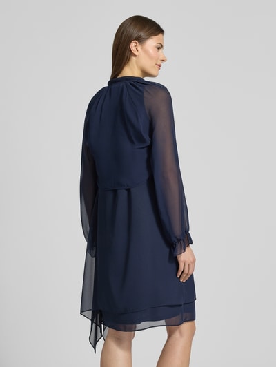 Frauenmodel trägt Relaxed Fit Bolero in semitransparentem Design von V.M., dunkelblau, elastische Ärmelabschlüsse mit Rüschenbesatz, langärmelig, Rückenlänge bei Größe 36: 41 cm, ganzkörperansicht Rückansicht.