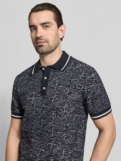 Männermodel trägt Regular Fit Poloshirt im Allover-Look von Jack & Jones Premium aus reiner Baumwolle mit Polokragen und Knopfleiste, Nahaufnahme Oberkörper.