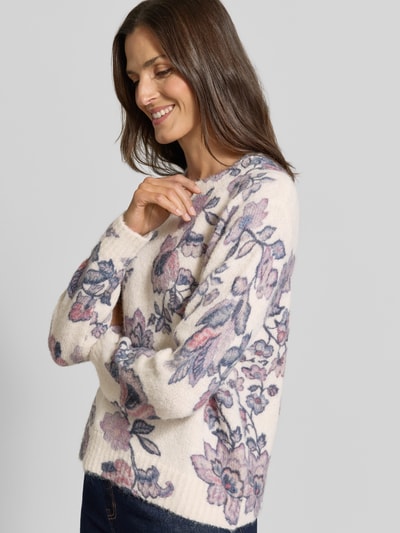 Vrouwenmodel draagt Relaxed Fit Strickpullover met leinen-anteil van Christian Berg Woman, elastische materiaalmix, ribboorden, bies, lange mouw, ruglengte bij maat S 57 cm, mouwlengte bij maat S 62 cm, lichtbeige met roze en blauwe bloemenprint, zachte textuur, geheel aanzicht schuin voor.