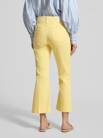 Vrouwenmodel draagt Bootcut Jeans im 5-Pocket-Design Modell 'Mary' van Brax, mix van katoen en lyocell met stretch, uitlopende snit, labeldetail, bandwijdte maat 36: 39 cm, binnenbeenlengte maat 36: 67 cm, gele kleur, gladde textuur, volledig lichaam achteraanzicht.