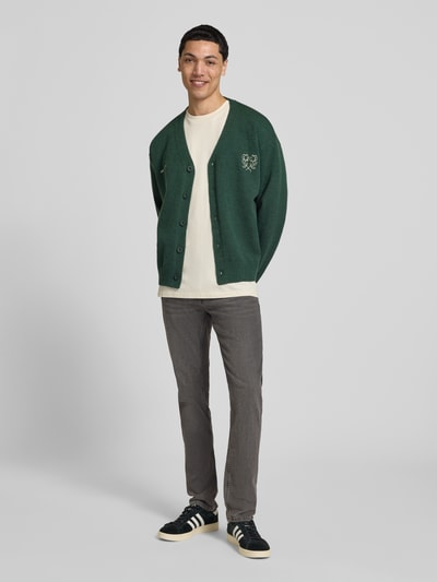 Männermodel trägt Slim Fit Jeans aus Baumwoll-Mix mit Viskose-Anteil Modell 'LOOM' von Only & Sons in grauer Denim-Optik, 5-Pocket-Design, Label-Prägung, Twill-Materialverarbeitung, Ganzkörperansicht von vorne.