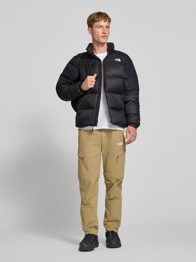Männermodel trägt Regular Fit Jacke mit Daunen-Feder-Füllung Modell 'Diabolo' von The North Face in Schwarz, Stepp-Optik, Ganzkörperansicht von vorne. Rückenlänge 70 cm, Schulterbreite 47 cm, Brustweite 58 cm, Ärmellänge 69 cm.