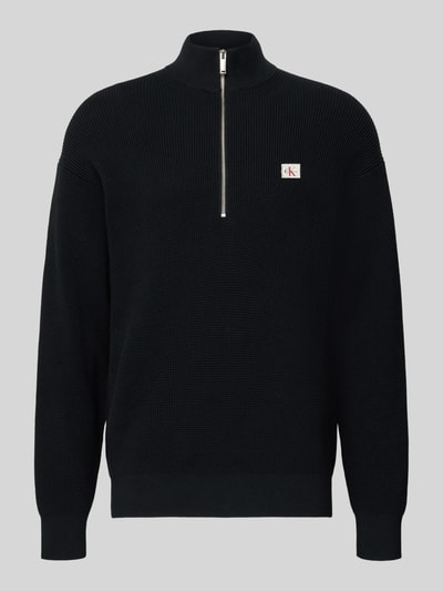 Produktfoto, schwarzer Loose Fit Troyer mit gerippten Abschlüssen und kurzem Reißverschluss von Calvin Klein Jeans, Label-Detail auf Brust.