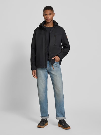 Männermodel trägt Jacke mit Reißverschlusstaschen von camel active in Schwarz, gerade Passform, mit Kapuze, Ganzkörperansicht von vorne.