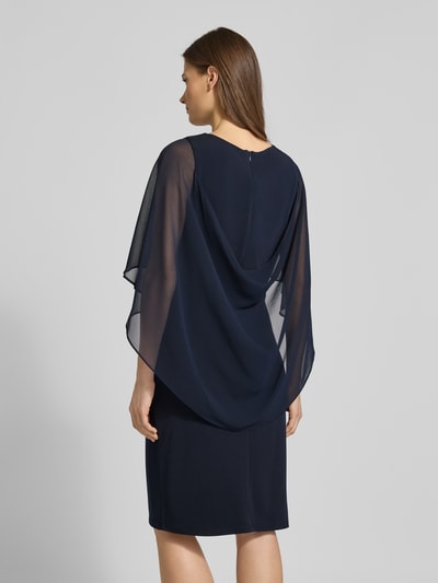 Frauenmodel trägt knielanges Cocktailkleid mit Rundhalsausschnitt von Vera Mont in Dunkelblau, elastischer Material-Mix, Chiffon-Fledermausärmel, Rückseitiger Nahtreißverschluss, Ganzkörperansicht Rückansicht.