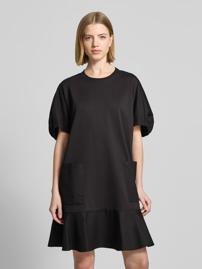 Frauenmodel trägt knielanges Tunika-Kleid mit Puffärmeln Modell 'ONORE' von Max Mara aus Baumwoll-Mix mit Stretch-Anteil, A-Linie, Rundhalsausschnitt, schwarze Farbe, glatte Textur, Zwei Fronttaschen, Ganzkörperansicht von vorne.