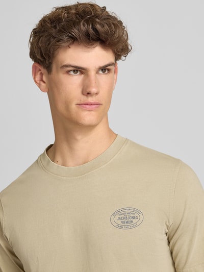 Männermodel trägt T-Shirt mit Label-Print Modell 'FELIX' von Jack & Jones Premium in Beige, reine Baumwolle, Nahaufnahme Oberkörper.