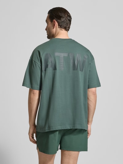 Männermodel trägt Boxy Fit T-Shirt mit Rundhalsausschnitt von HALO, Reine Baumwolle, überschnittene Schultern, Grün, Rückenlänge 71 cm, Ganzkörperansicht Rückansicht.