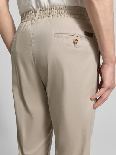 Männermodel trägt Regular Fit Stoffhose mit Logo-Detail Modell 'Lester' von JOOP! Collection, beige, Baumwoll-Mix, Nahaufnahme Rückansicht.