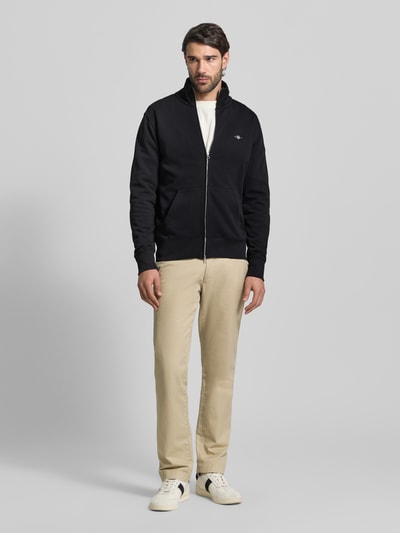 Männermodel trägt Regular Fit Sweatjacke mit Stehkragen Modell 'Gield' von Gant in Schwarz, Baumwoll-Mix, Ganzkörperansicht von vorne.