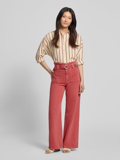 Frauenmodel trägt Wide Leg Jeans mit Gürtel von Jake*s Casual in Reine Baumwolle, AufgesetzteTaschen, rosafarbene Textur, Ganzkörperansicht von vorne.