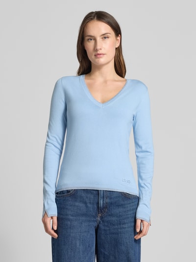 Frauenmodel trägt Slim Fit Longsleeve aus Viskose-Mix mit V-Ausschnitt von Liu Jo White in Hellblau, Logo-Detail, elastische Abschlüsse, Ganzkörperansicht von vorne