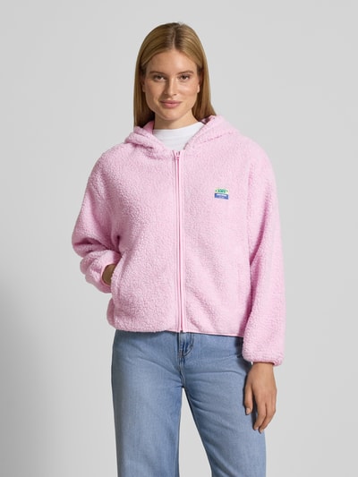 Frauenmodel trägt Jacke aus Teddyfell Modell 'HOKTOWN' von American Vintage in Rosa mit Kapuze, Reißverschluss, Label-Detail und Eingrifftaschen, Regular-Fit, Ganzkörperansicht von vorne.