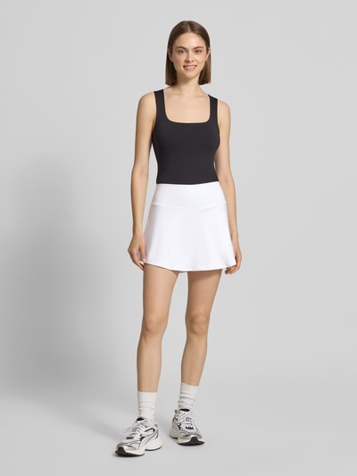 Frauenmodel trägt Minirock im 2-in-1-Look mit Logo von NIKE TRAINING, A-Linie, weiß, elastischer Bund, Ganzkörperansicht von vorne.