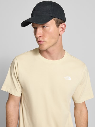 Mannenmodel draagt 'T-Shirt mit Label-Stitching' van The North Face in beige, katoenmix, regular fit, ronde hals, bovenlichaam close-up.