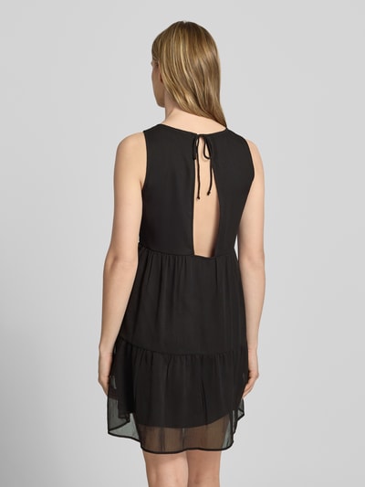 Frauenmodel trägt Regular Fit Chiffonkleid in Crêpe-Optik Modell 'LARA' von Pieces, Unifarben, Mini-Länge, Bindeband, Cut-Out, Rückansicht.