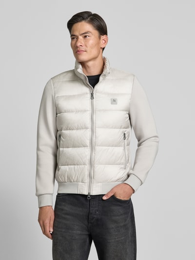 Männermodel trägt Jacke mit Label-Patch und Stehkragen von Antony Morato in licht beige, gesteppt, mit tweewegritssluiting, zij-ritszakken, elastische boorden, slim fit, ruglengte 67 cm, schouderbreedte 48 cm, borstwijdte 56 cm, mouwlengte 67 cm, Ganzkörperansicht van voren