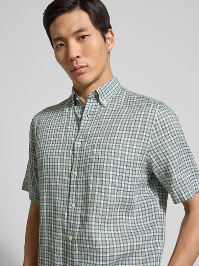 Männermodel trägt Regular Fit vrijetijdsoverhemd uit linnen van Christian Berg Men, button-downkraag, knoopsluiting, borstzak, pastelgroene en lichtblauwe ruit, ruglengte maat M 81 cm, schouderbreedte 54 cm, mouwlengte 28 cm, Nahaufnahme Oberkörper.