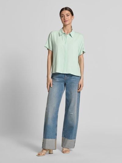 Modelka nosi Relaxed Fit Kurzarmbluse aus Viskose od Tom Tailor Denim, jasny jednolity kolor, krótki rękaw, materiał wiskozowy, widok całej sylwetki z przodu.