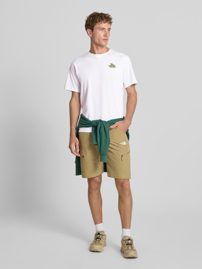 Männermodel trägt Regular Fit T-Shirt mit Motiv-Print auf der Rückseite von The North Face in Weiß, reine Baumwolle, Ganzkörperansicht von vorne