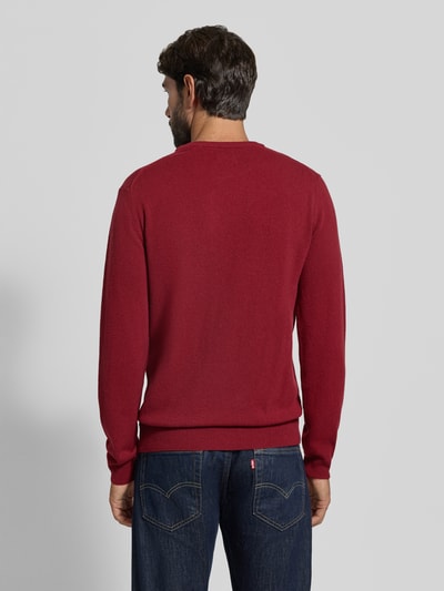 Männermodel trägt Regular Fit Pullover aus reiner Wolle von GANT in Dunkelrot mit feiner Strickstruktur, Ganzkörperansicht Rückansicht.