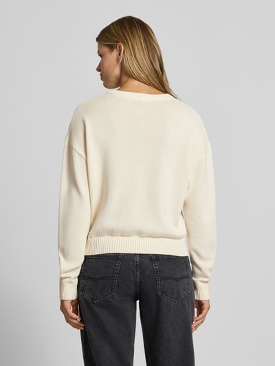 Frauenmodel trägt Strickpullover aus reiner Baumwolle von REVIEW in Creme mit lockerer Passform und gerippten Abschlüssen, Ganzkörperansicht Rückansicht.
