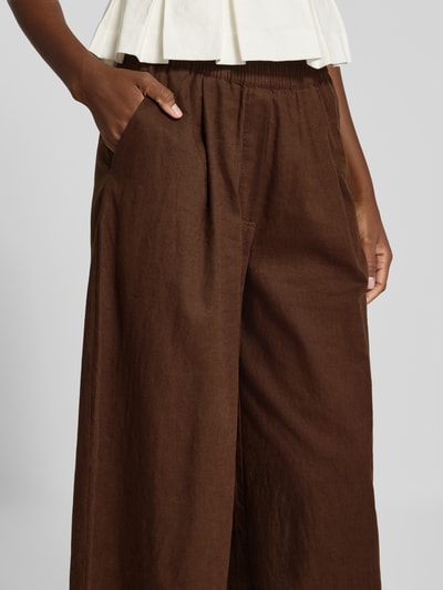 Frauenmodel trägt Wide Fit Leinen-Hose aus Leinen-Mix von Rich & Royal in Braun, elastischer Bund, Bundfalten, Nahaufnahme Oberkörper.