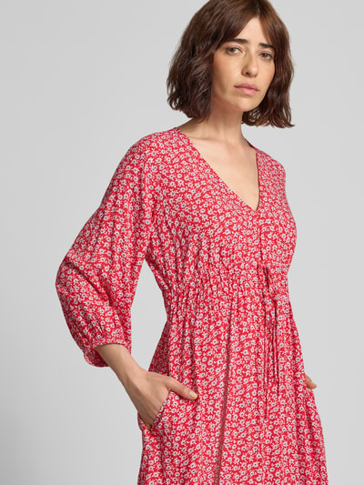 Frauenmodel trägt Minikleid aus reiner Viskose mit floralem Allover-Print von GAP in Rot mit weißen Blumen, taillierte Passform, V-Ausschnitt, 3/4-Arm, Nahaufnahme Oberkörper.