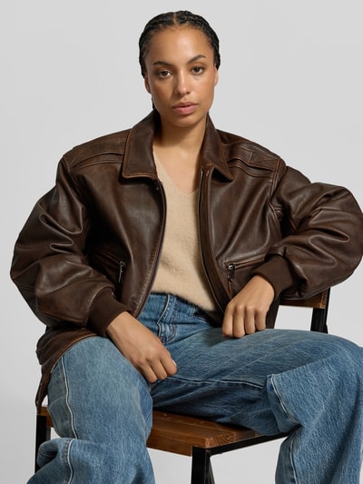 Frauenmodel trägt Relaxed Fit Jacke aus reiner Viskose von Rabanne in brauner Leder-Optik, kombiniert mit Jeans, Nahaufnahme Oberkörper, Damenjacke mit Eingrifftaschen und durchgängiger Abdeckleiste, Rückenlänge und Brustweite bei Größe 38: 68 cm bzw. 54 cm, Ärmellänge 66 cm.