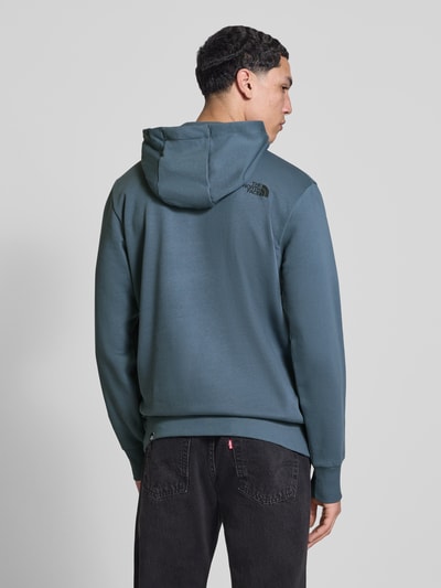 Männermodel trägt Regular Fit Hoodie mit Logo-Print von The North Face in Blau, elastische Abschlüsse, Rückansicht, Ganzkörperansicht Rückansicht. Baumwoll-Mix, Kapuze mit Tunnelzug, Känguru-Tasche, Rückenlänge 69 cm, Ärmellänge 71 cm.