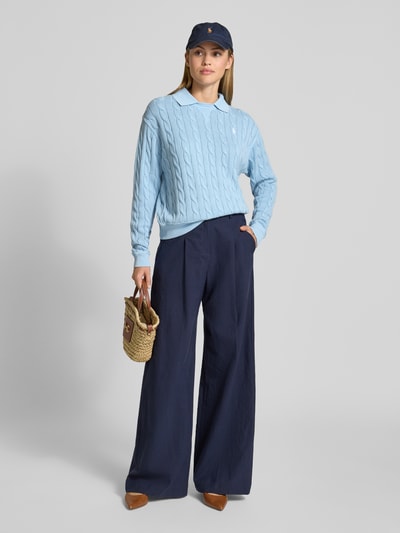 Frauenmodel trägt Regular Fit Pullover mit Polokragen von Polo Ralph Lauren, hellblau, Zopfstrick aus reiner Baumwolle, Logo-Stitching, unifarben, Ganzkörperansicht von vorne.
