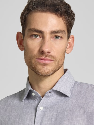 Männermodel trägt Slim Fit Business-Hemd aus Leinen mit Kentkragen von SEIDENSTICKER, reine Leinen, Nahaufnahme Oberkörper. Rückenlänge bei Größe 40: 69 cm, Schulterbreite: 43 cm, Ärmellänge: 64 cm, Knopfleiste, hellgraue Farbe, feine Leinenstruktur.