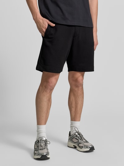 Männermodel trägt schwarze Regular Fit Sweatshorts aus Baumwoll-Mix Modell 'JT_SHORTS' von BOSS Green, Ganzkörperansicht von vorne.