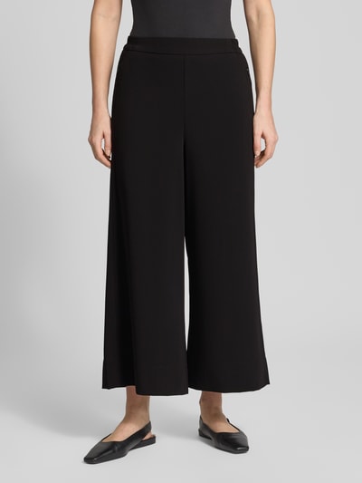 Frauenmodel trägt schwarze Stoffhose in verkürzter Passform Modell 'Coralie' von MAC, elastischer Bund, Nahtreißverschlusstaschen, Nahaufnahme Oberkörper.