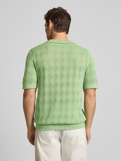 Männermodel trägt Regular Fit Poloshirt aus reiner Baumwolle Modell 'ARCO' von SELECTED HOMME, Lochstrickmuster, Ganzkörperansicht Rückansicht.