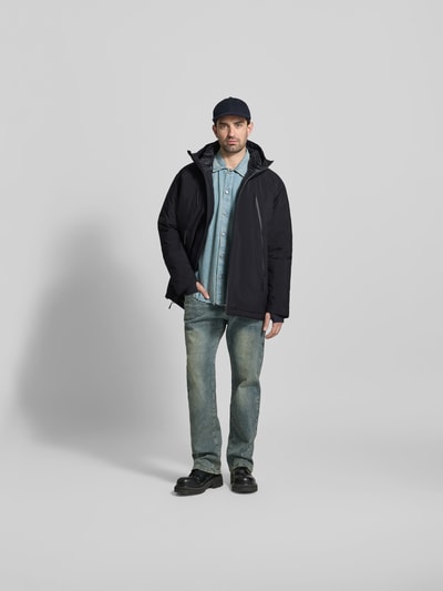 Männermodel trägt Daunenjacke mit Daunen-Feder-Füllung von MM6 Maison Margiela in Schwarz, lockere Passform, Ganzkörperansicht von vorne.