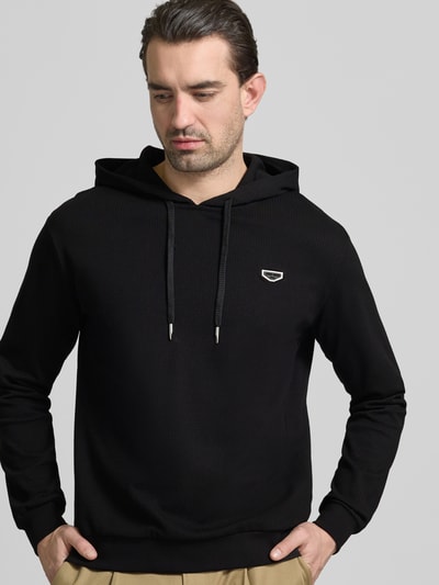Männermodel trägt Regular Fit Hoodie in Strick-Optik von Antony Morato, Baumwoll-Mix, Schwarz, Kapuze, elastische Abschlüsse, Nahaufnahme Oberkörper.