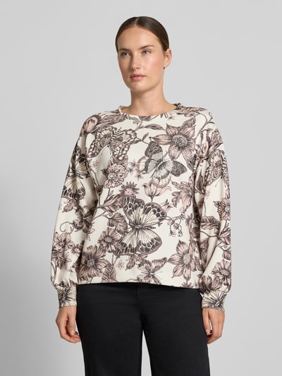 Frauenmodel trägt Regular Fit Bluse aus Viskose-Mix von monari mit floralem Allover-Print in Creme und Braun, Nahaufnahme Oberkörper.
