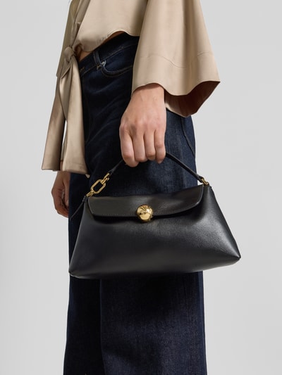 Frauenmodel trägt Umhängetasche mit Label-Detail Modell 'SFERA' von FURLA, schwarze glatte Oberfläche, Nahaufnahme Unterkörper. Hauptfach mit Umschlag und Druckknopfverschluss, Schultergurt, Maße 22 cm Breite, 14 cm Länge, 9 cm Tiefe, Riemenlänge 110 cm.