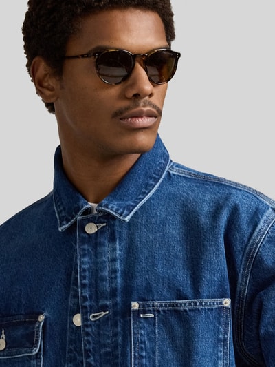 Mannelijk model draagt Regular Fit Jeansjacke aus reiner Baumwolle van Polo Ralph Lauren in effen denimblauw, close-up bovenlichaam.